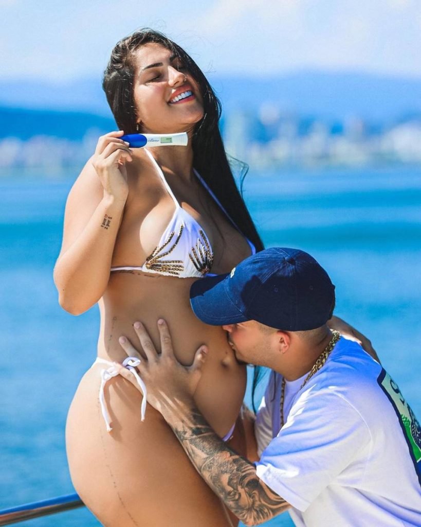 Jottapê beija a barriga de Estefany Boro enquanto ela sorri e segura teste de gravidez - metrópoles