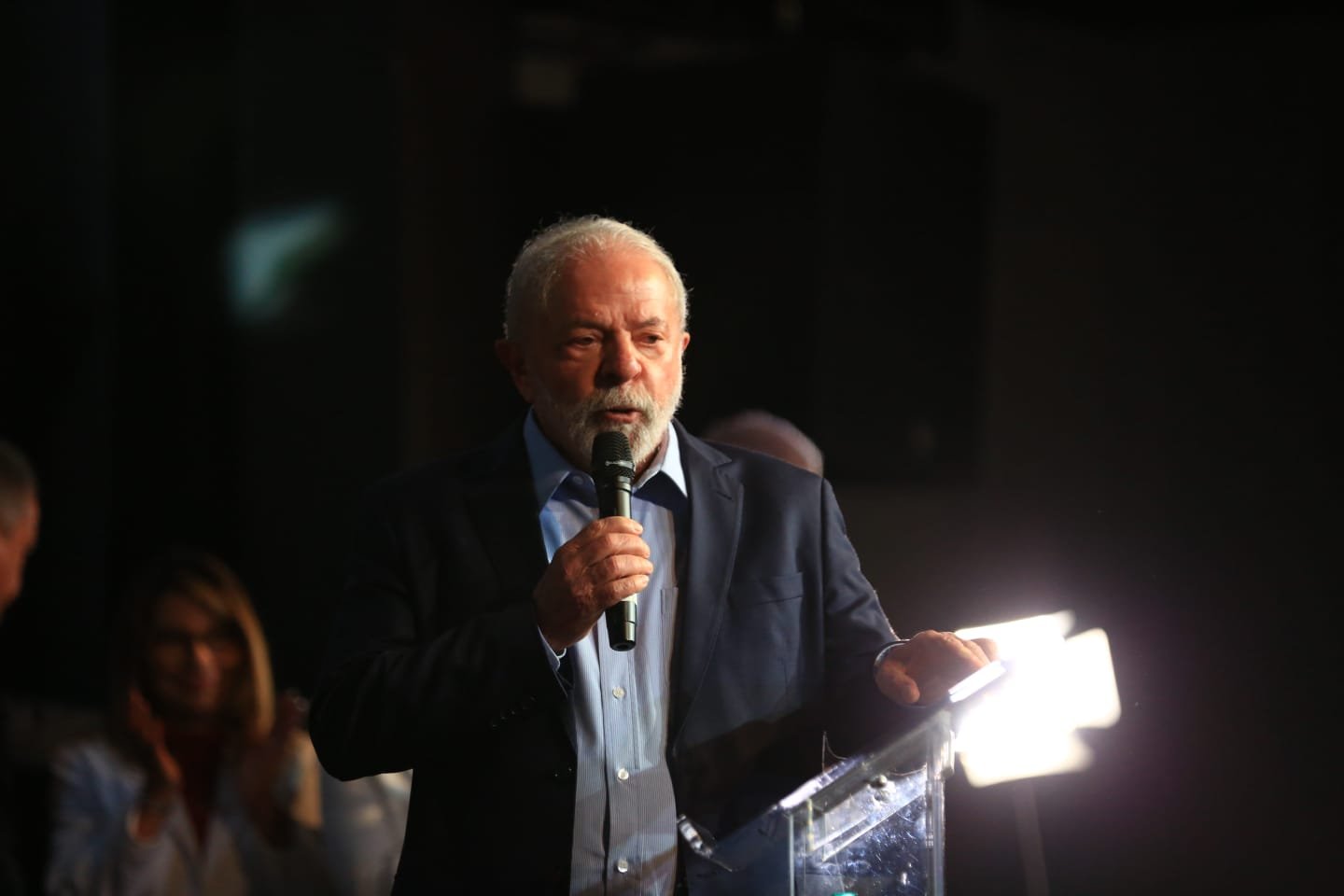 O presidente eleito Lula em coletiva de impresa para anúncio de novos ministros para o próximo governo. Ele fala em púlpito diante de microfone - Metrópoles