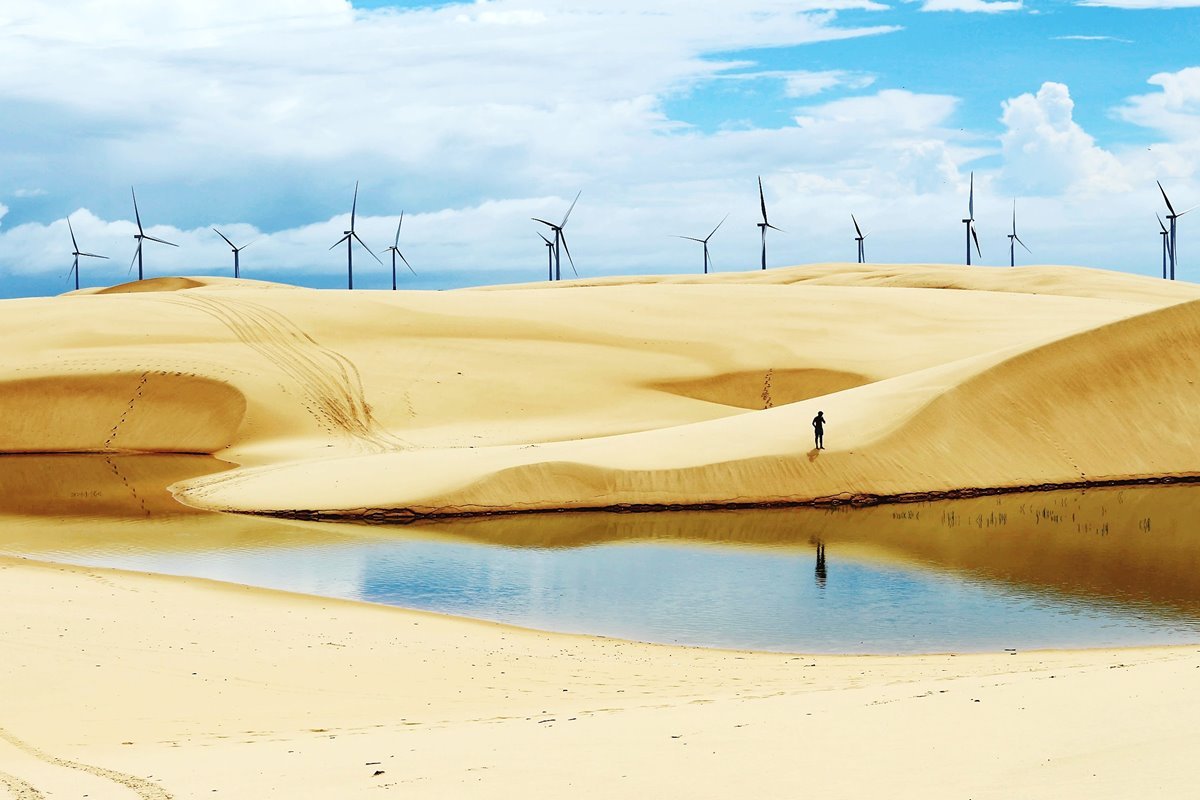Foto colorida de dunas com geradores de energia eólica - Metrópoles