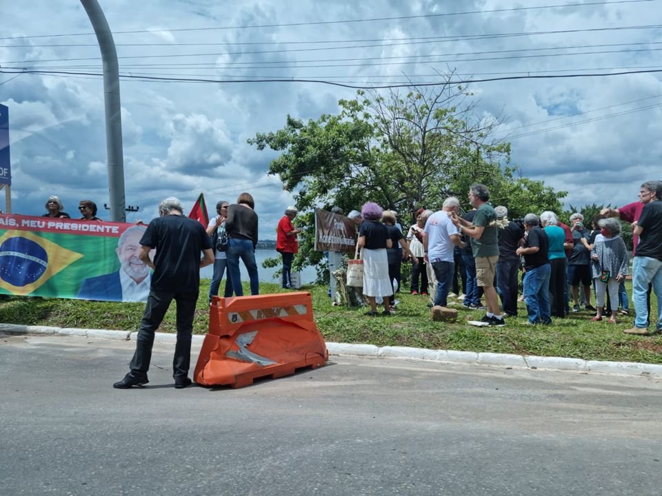 Pessoas em gramado ao lado de placa em dia nublado