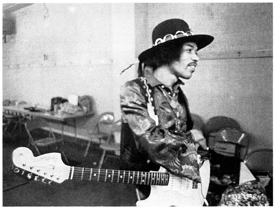 Foto em preto e branco de Jimi Hendrix com um chapéu e uma guitarra