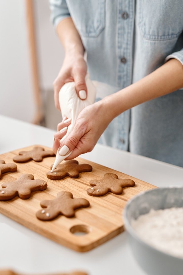 Mãos de mulher confeitando biscoitos em mesa - Metrópoles