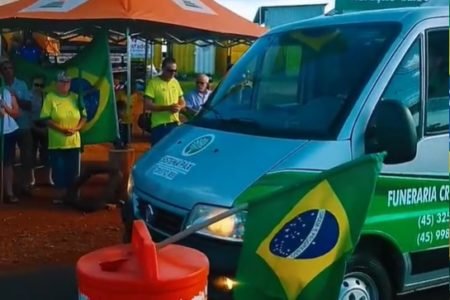 Imagem colorida: carro funerário parado em frente a acampamento de "patriotas" - Metrópoles