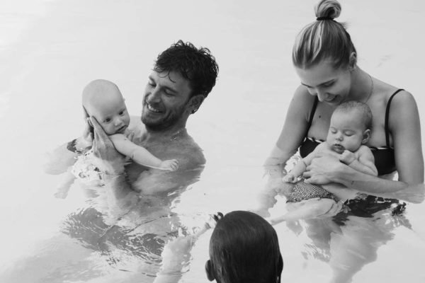 Isa Scherer e Rodrigo Calazans com os filhos Mel e Bento na piscina em foto preto e branco - metrópoles