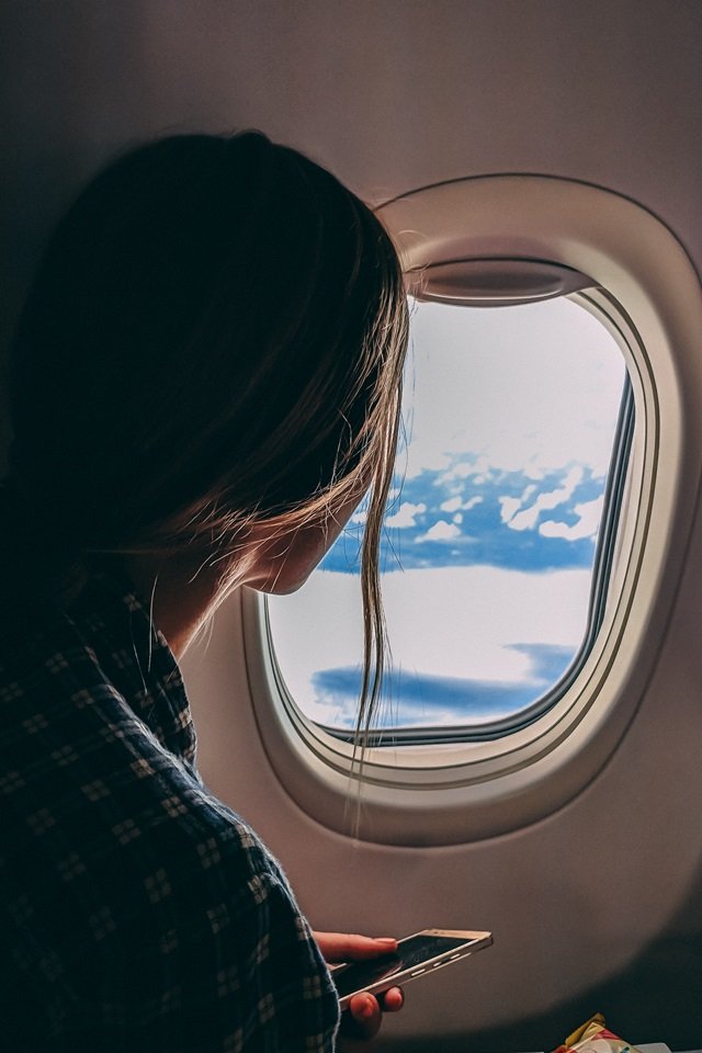 Mulher de costas olhando para a janela de avião - Metrópoles