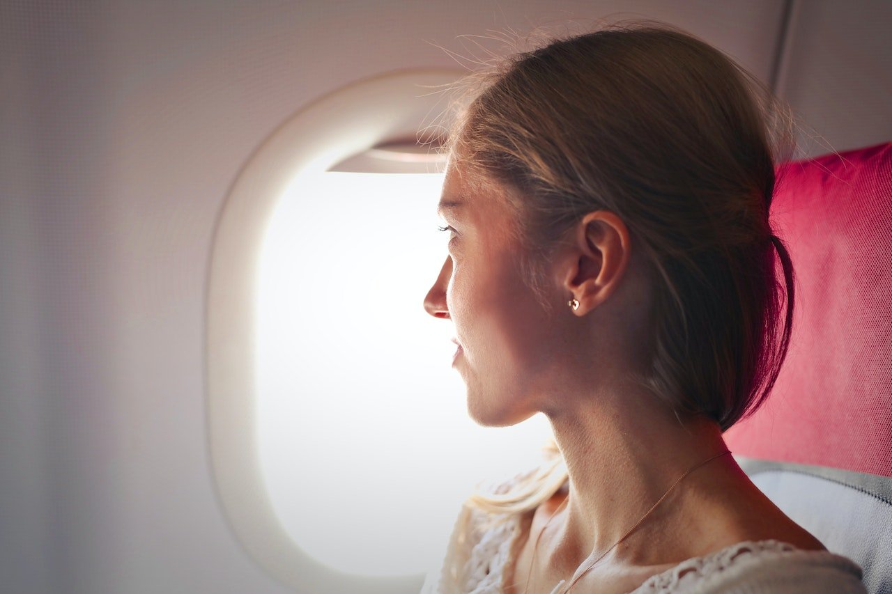 Mulher sentada em avião olhando para a janela - Metrópoles