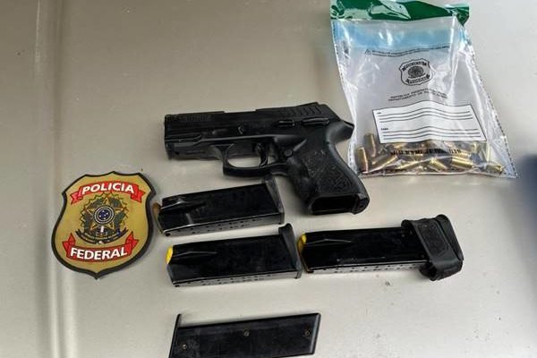 Arma, cartuchos e projéteis aparecem espalhados em mesa ao lado de distintivo da Polícia Federal após serem apreendidos com bolsonarista suspeito de ataque à PF - Metrópoles