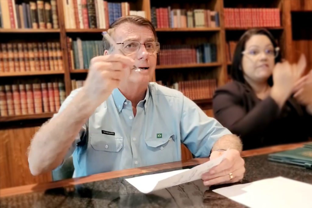 O presidente Bolsonaro, há dois dias de deixar o cargo, faz live no palácio do Alvorada antes de terminar mandato. Ele fala na biblioteca diante da mesa, ao lado de uma tradutora - Metrópoles