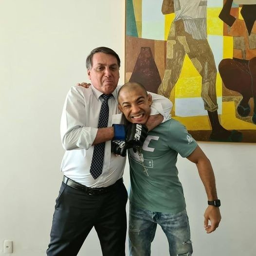 Fighter Jose Aldo and President Jair Bolsonaro pose for a photo, smiling, with the athlete receiving a 