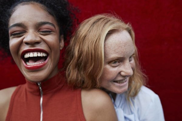 Duas meninas gargalhando abraçadas