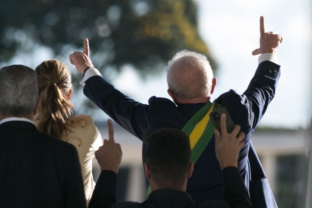 Lula faz sinal L com as mãos para apoiadores que acompanham a posse no palacio do Planalto - Metrópole