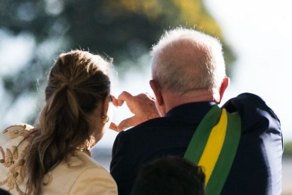 A primeira-dama Janja e o presidente Lula aparecem de costas fazendo coração com as mãos - Metrópoles