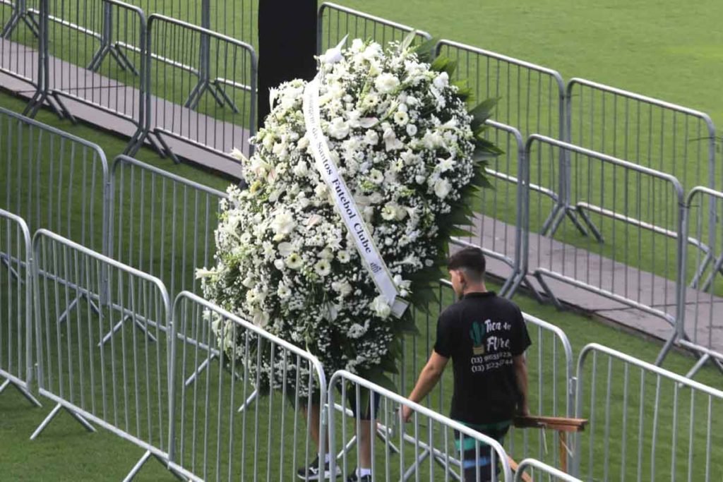 Homem carregando coroa de flores para o velório do ex-jogador Pelé na Vila Belmiro, estádio do Santos - Metrópoles