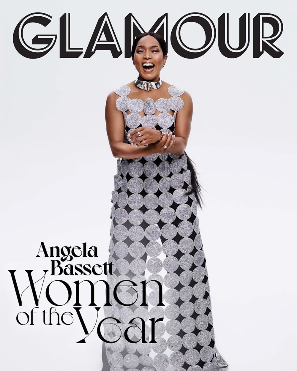 A atriz Angela Bassett, uma mulher negra de meia idade, na capa da revista Glamour do Reino Unido. Ela usa um vestido prata bordado e um colar com argolas, também prata. - Metrópoles