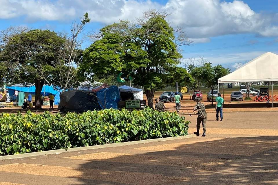 Acampamento bolsonarista no QG do Exército amanhece vazio, com estruturas desfeitas e lixo nas ruas após a posse do presidente Lula. No detalhe, homens desarmam toldo - Metrópoles