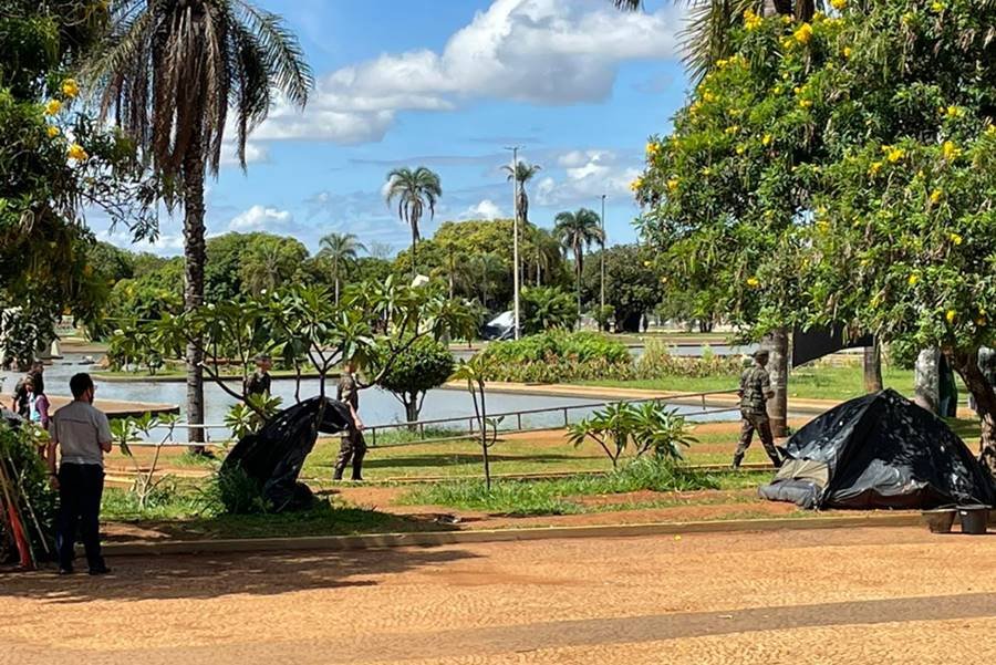 Acampamento bolsonarista no QG do Exército amanhece vazio, com estruturas desfeitas e lixo nas ruas após a posse do presidente Lula. No detalhe, homens desarmam toldo - Metrópoles