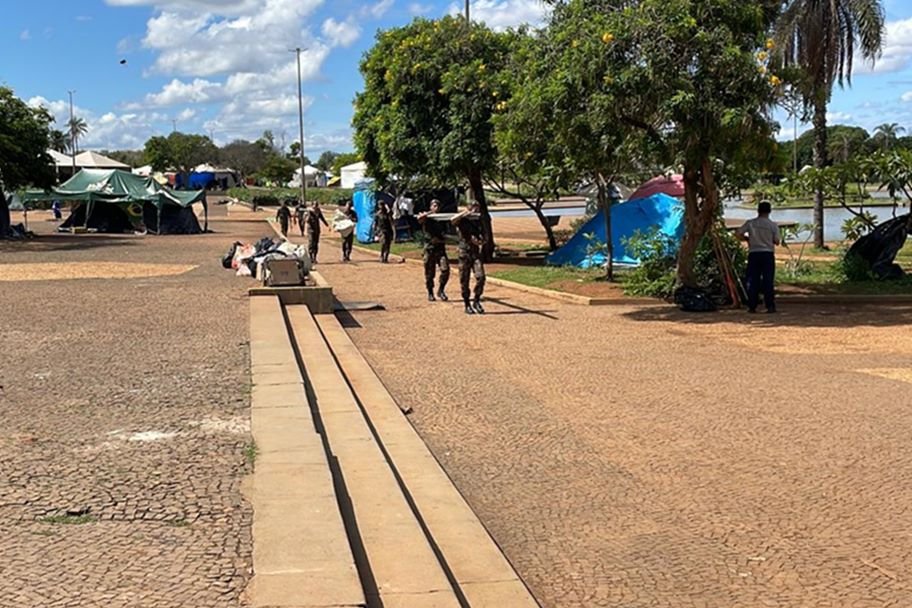 Acampamento bolsonarista no QG do Exército amanhece vazio, com estruturas desfeitas e lixo nas ruas após a posse do presidente Lula. No detalhe, homens desarmam toldo - Metrópoles