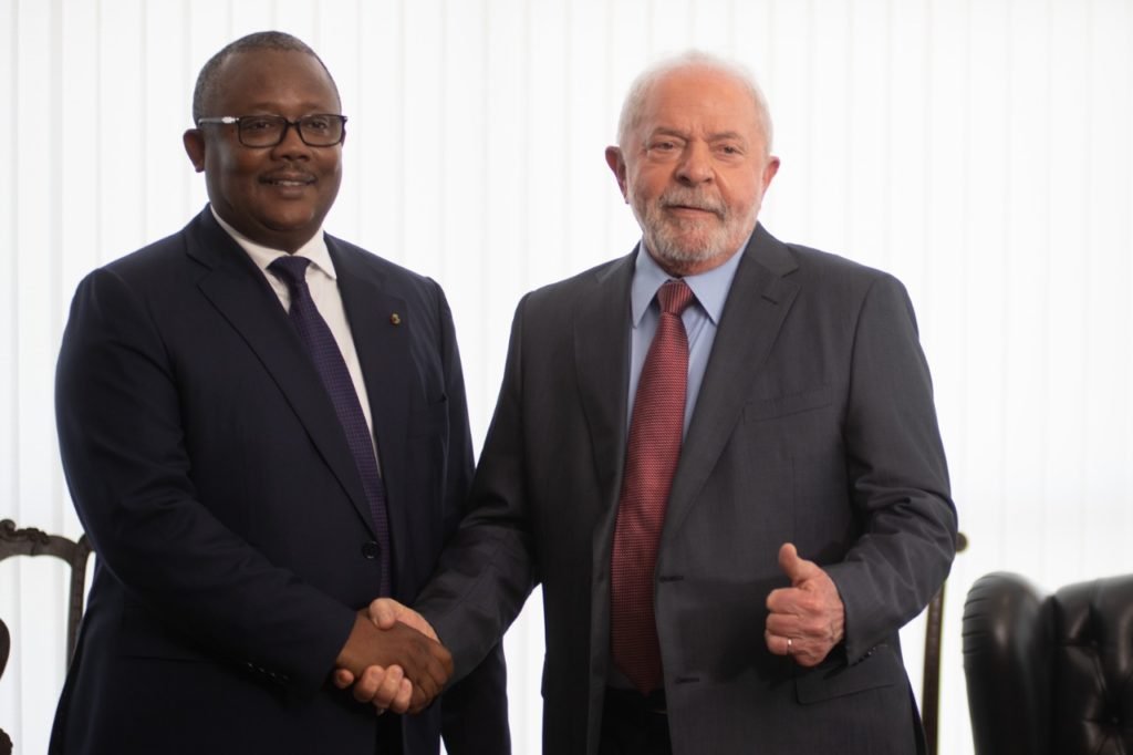 O presidente da Guiné-Bissau, Umaro Sissoco Embaló, posa com Lula para foto enquanto apertam as mãos. Ambos sorriem - Metrópoles
