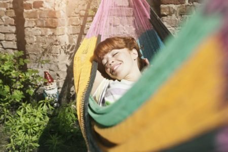 Foto colorida de mulher dorrindo deitada em uma rede - Metrópoles