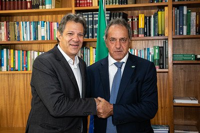Ministro da Fazenda Fernando Haddad se reúne com Scioli, embaixador argentino no Ministério para reunião. Na imagem, ambos posam apertando as mãos para foto frente a estante de livros - Metrópoles
