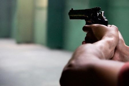 Imagem mostra arma de fogo nas mãos de uma pessoa. Política de armas - Metrópoles