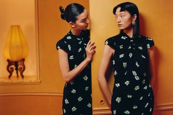 Duas mulheres asiáticas em editorial de moda. Elas estão se olhando e usando vestidos com a mesma estampa - Metrópoles