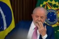 O presidente Lula faz primeira reunião ministerial no Palácio do Planalto e pede boa relação com o Congresso Nacional. Na imagem ele sentado, pensativo e com a mão no rosto, com bandeiras do Brasil atrás - Metrópoles