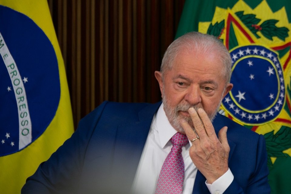O presidente Lula faz primeira reunião ministerial no Palácio do Planalto e pede boa relação com o Congresso Nacional. Na imagem ele sentado, pensativo e com a mão no rosto, com bandeiras do Brasil atrás - Metrópoles