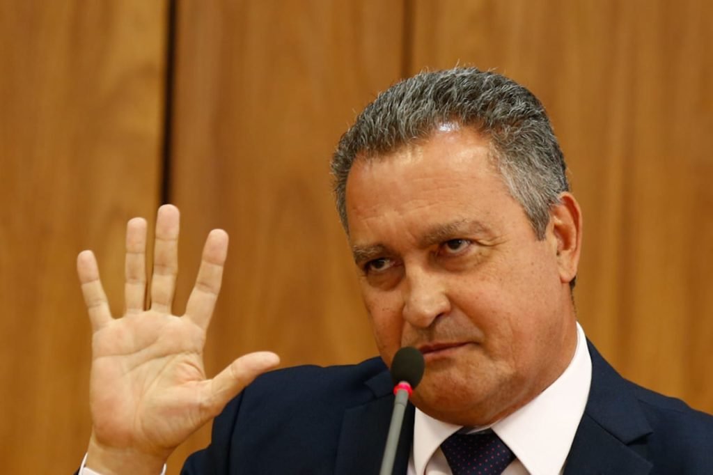 Ministro da Casa Civil, Rui Costa, concede entrevista coletiva sobre primeira reunião ministerial do governo Lula. Ele fala diante de microfone, sentado diante de mesa, e gesticula - Metrópoles