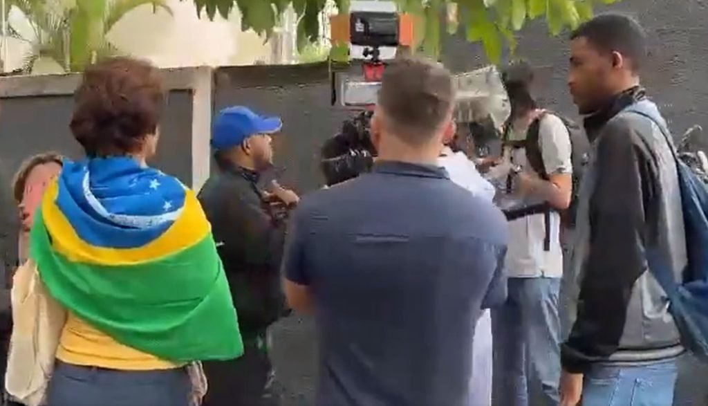 Jornalistas da Band são agredidos por militantes bolsonaristas e tem equipados quebrados em Belo Horizonte. Na imagem, eles são cercados por vários homens e uma mulher com bandeira do Brasil ataca uma das câmeras - Metrópoles