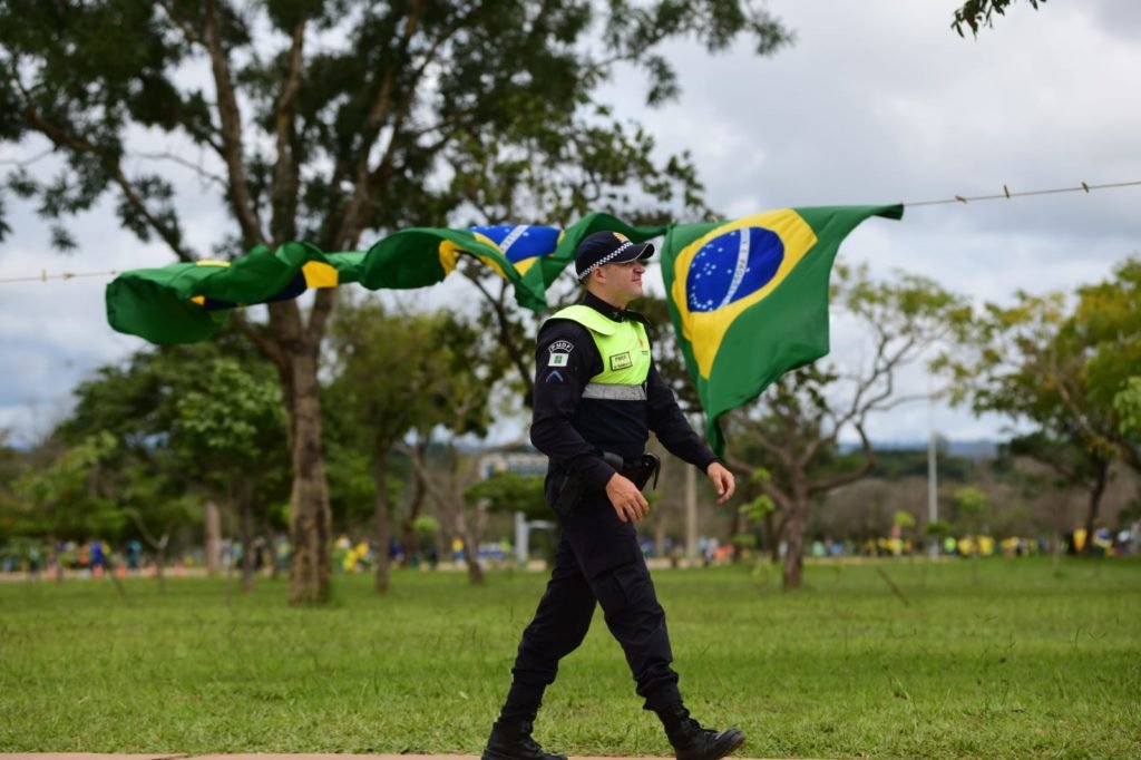 Policial militar fardado passa por bandeiras do brasill - Metrópoles
