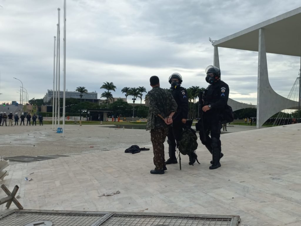 Manifestantes bolsonaristas presos no Palácio do Planalto durante protestos antidemocráticos na Esplanada dos Ministérios. Agentes da força de segurança sobem e descem rampa do Planalto, levando um homem preso que veste farda - Metrópoles