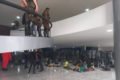 fotografia colorida mostra homens deitados no chão com exército em pé