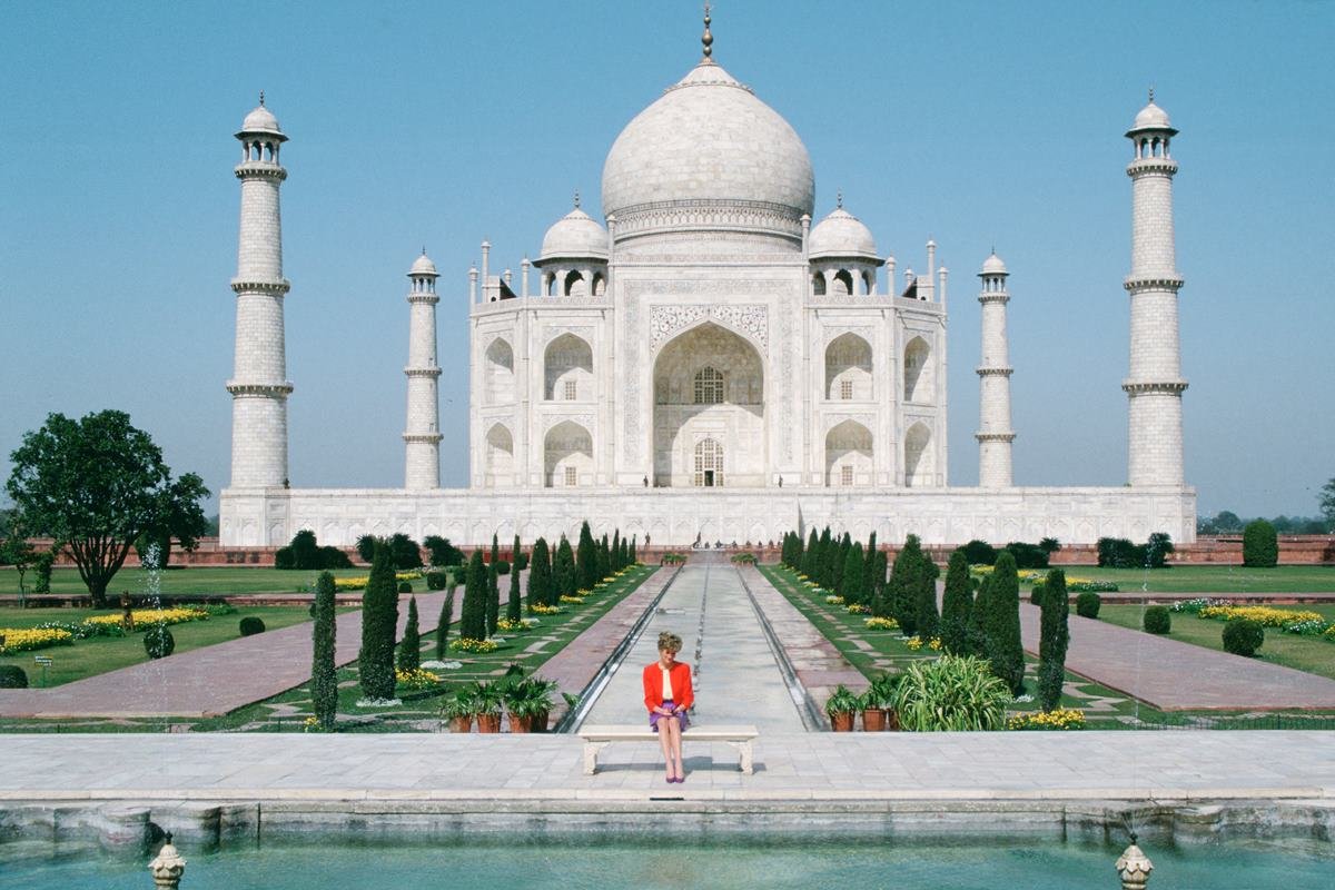 Foto colorida de mulher sentada em um banco e atrás está o monumento Taj Mahal - Metrópoles