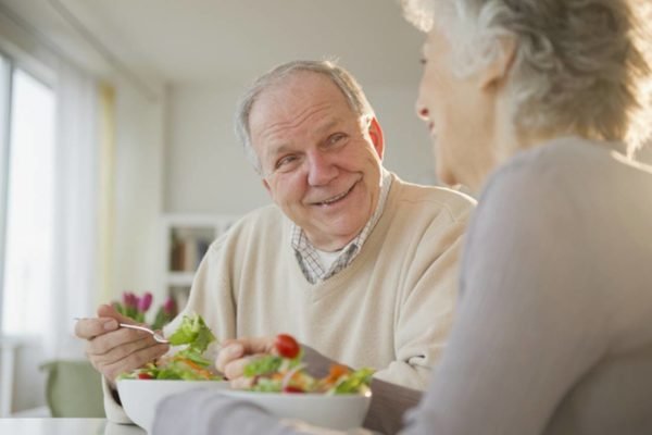 Casal de idoso saudáveis felizes enquanto comem salada