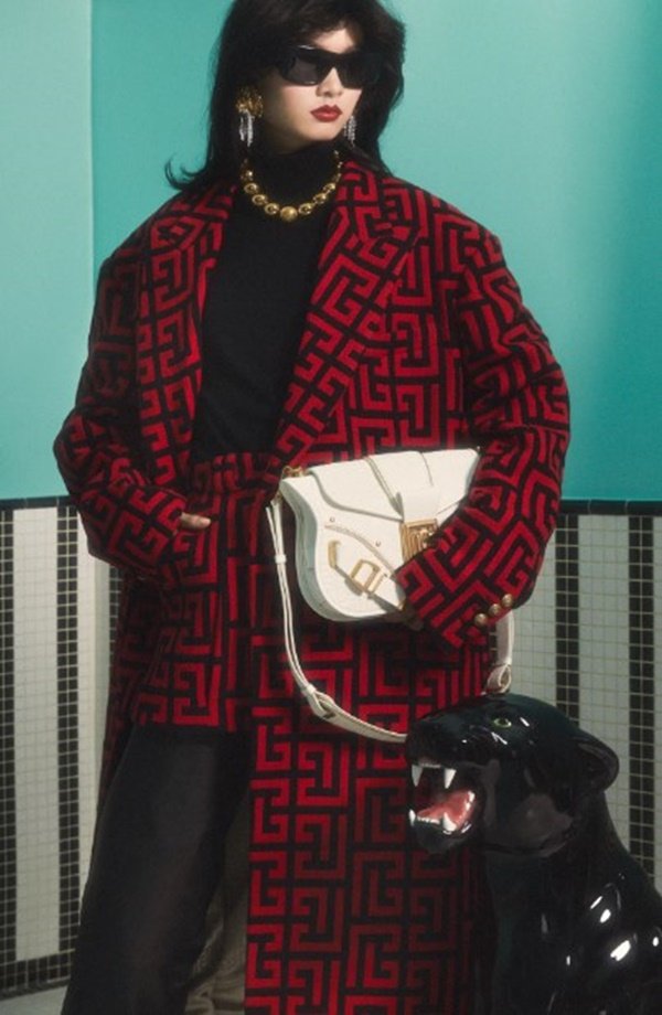 Mulher com roupas de outono em editorial de moda. Ela está posicionada em frente a uma parede azul - Metrópoles