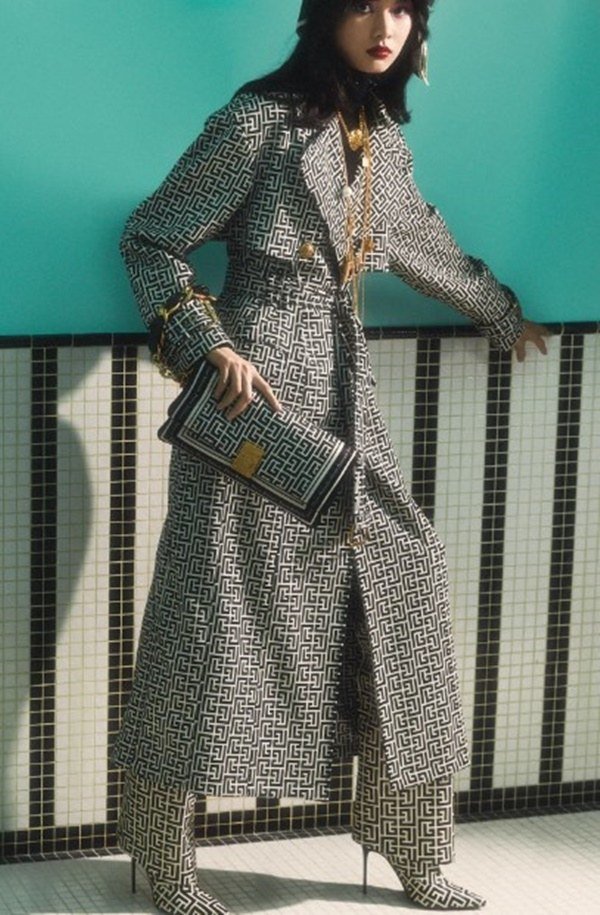 Mulher com roupas de outono em editorial de moda. Ela está posicionada em frente a uma parede azul - Metrópoles