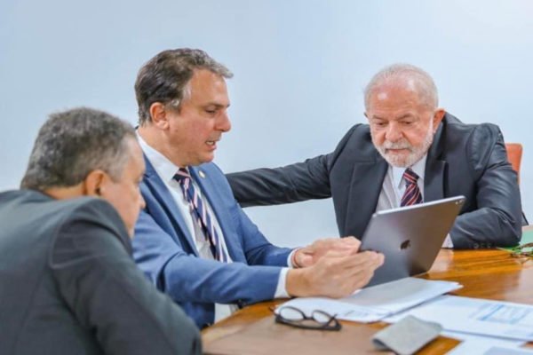 O presidente Lula assiste apresentação que o ministro da Educação, Camilo Santana, mostra em tablet. Estão sentados em mesa - Metrópoles