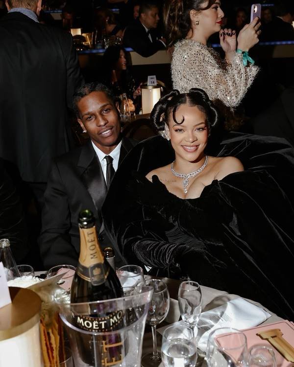 A$AP Rocky e Rihanna, sentado em mesa, no Globo de Ouro 2023 - Metrópoles