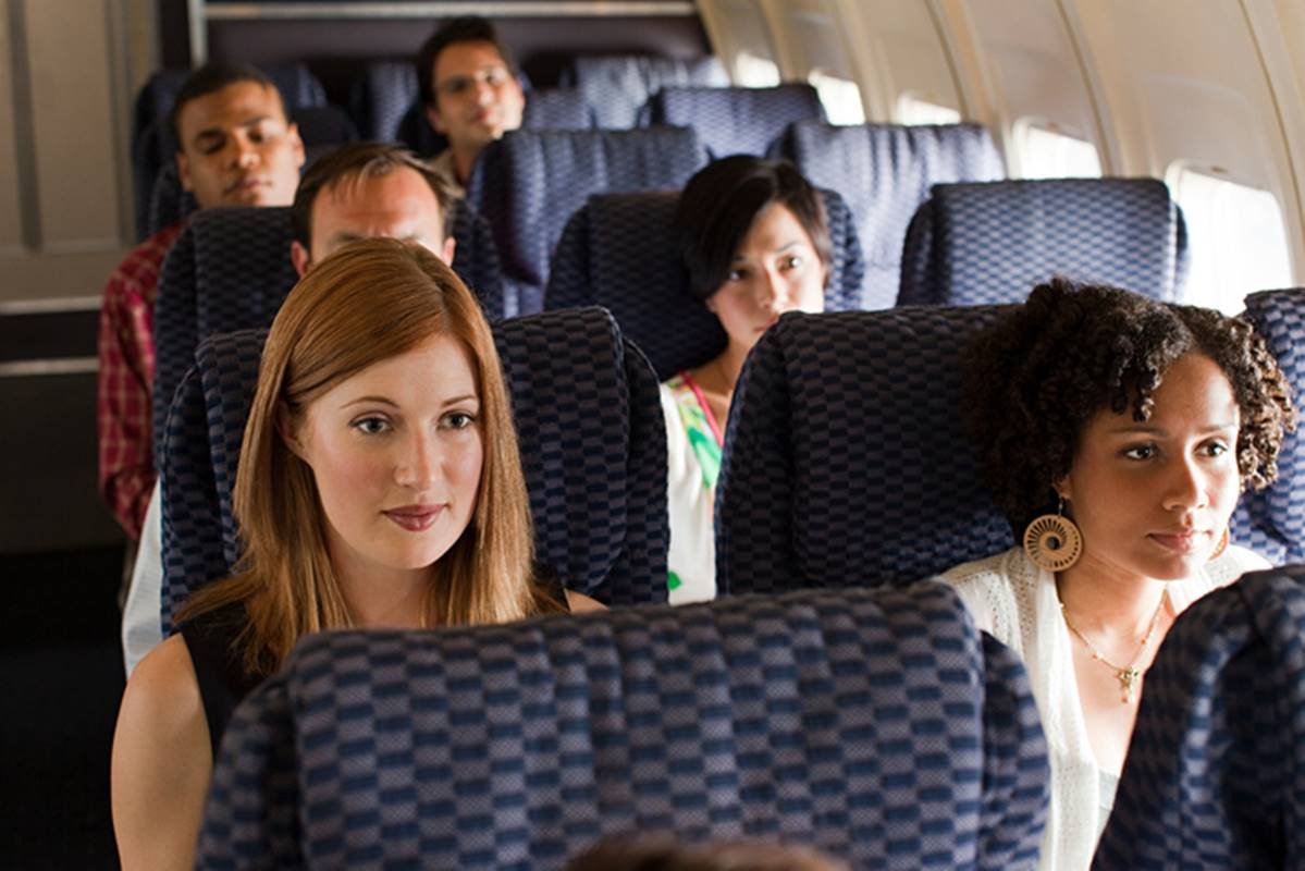 Fileira de cadeiras lotadas dentro do avião