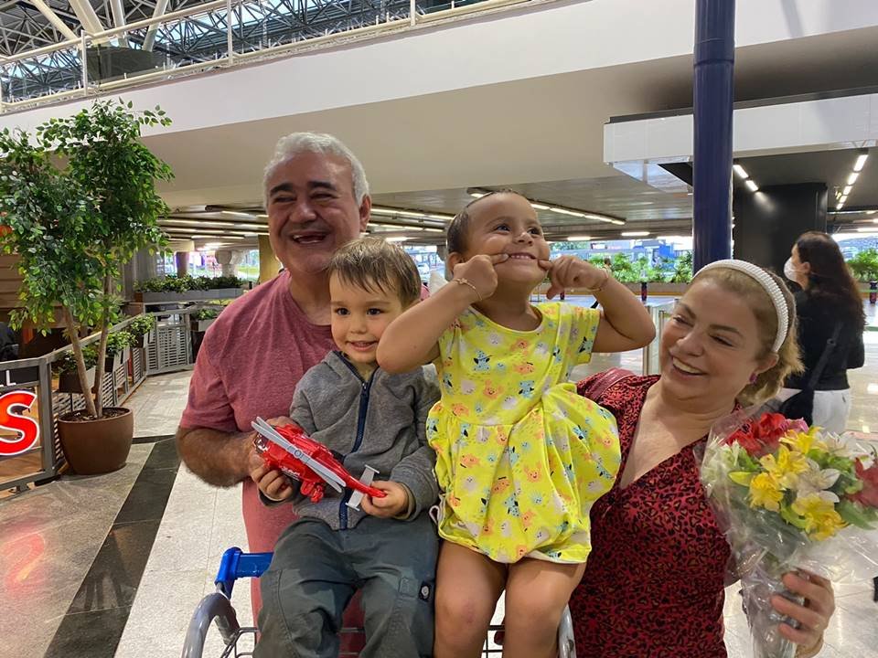 Foto de um homem à esquerda e uma mulher à direita com duas crianças no colo