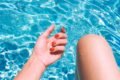 Mão de uma mulher branca com unhas vermelhas, na piscina. - Metrópoles
