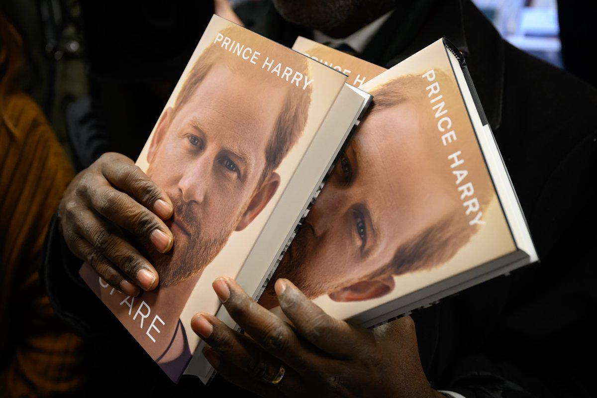 Mãos de uma pessoa negra seguram o livro do príncipe Harry
