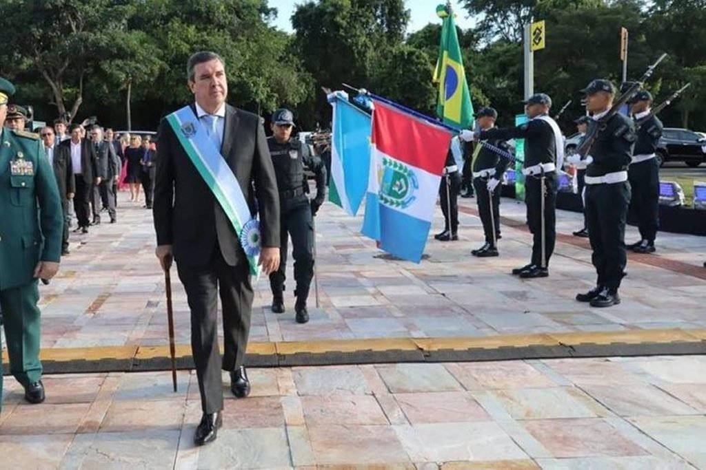 homem anda com ajuda de bengala enquanto pessoas estão nos arredores enfileirados com bandeiras - metrópoles