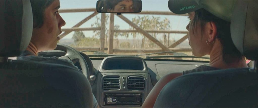 bancos de carro com uma mulher sentada em cada e uma porteira a frente - metrópoles