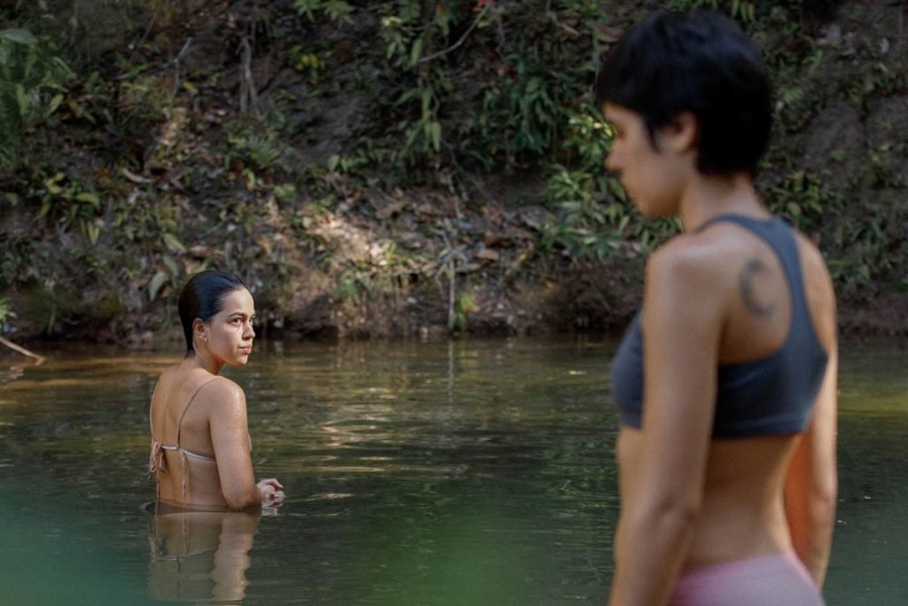 mulher de costas dentro de rio enquanto outra entra - metrópoles