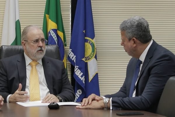 O procurador-geral da República conversa com o presidente da Câmara dos Deputados, Arthur Lira. Ambos estão sentados à mesa - Metrópoles