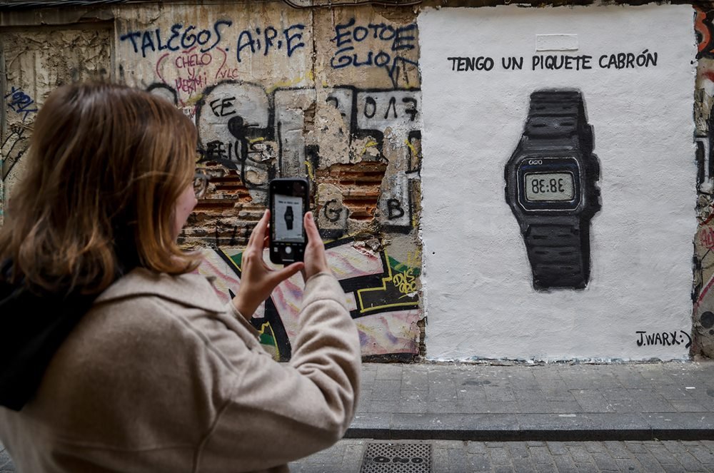Uma mulher tira uma foto de grafite em um relógio Casio com o texto 'tengo un piquete cabron' após a música de Shakira para Piqué, em 16 de janeiro de 2023 em Valência, Comunidade Valenciana, Espanha. - Metrópoles