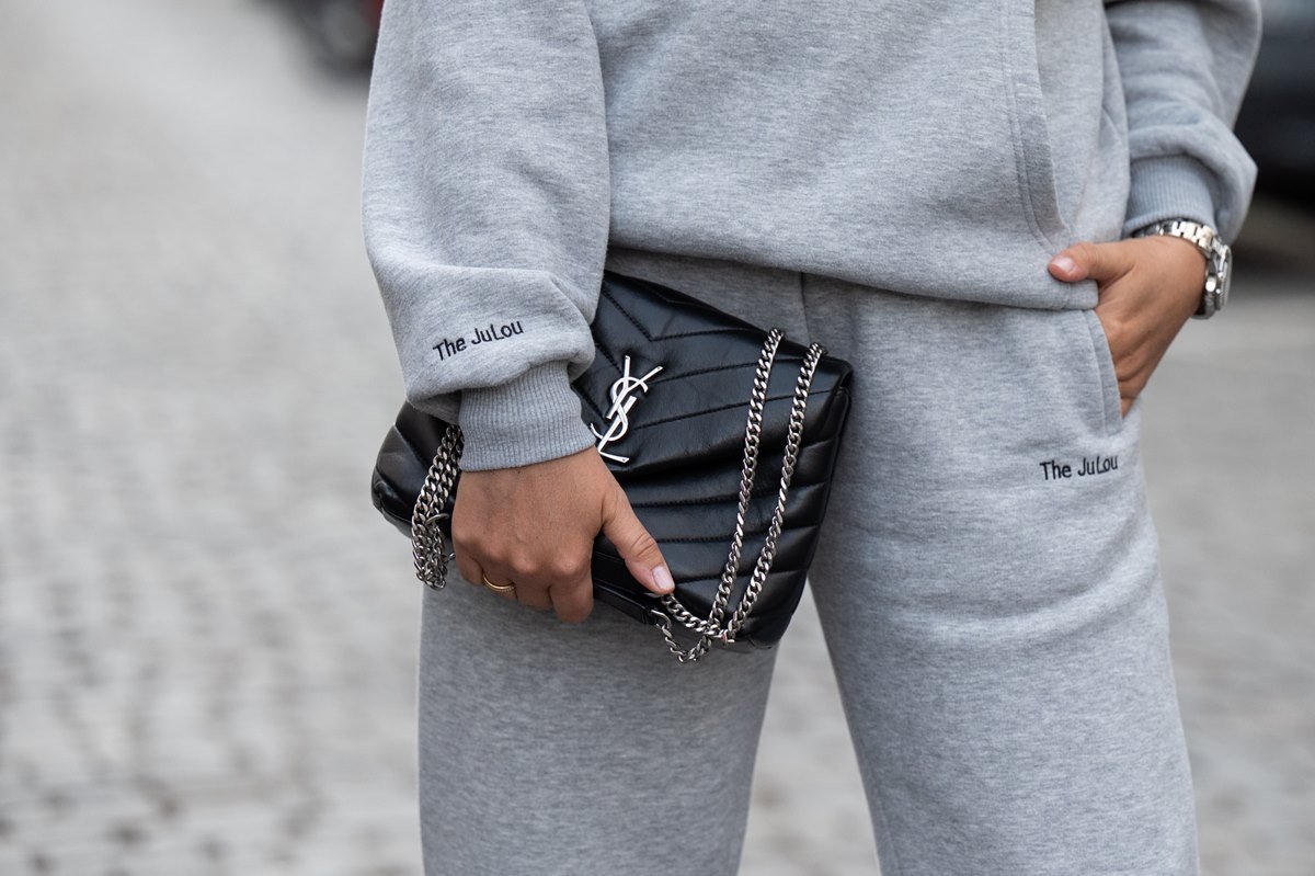 Mulher branca segura a bolsa Loulou, preta e de couro, da marca Saint Laurent. - Metrópoles