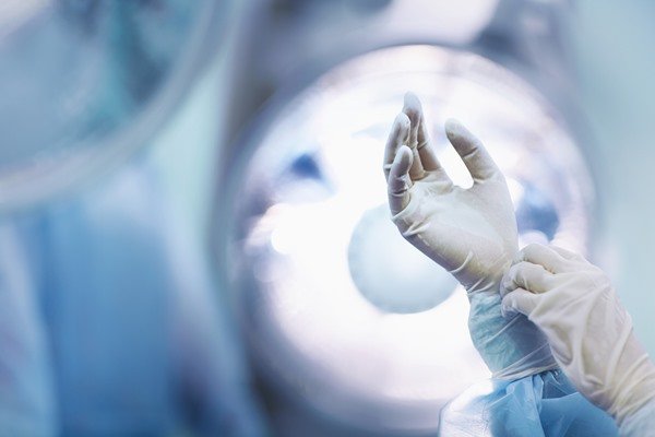 Color image of one hand holding the other in a surgical glove